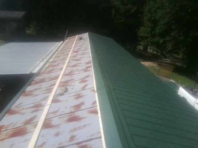 Old rusted panels beside newly installed green metal roofing — Wind Damage Roof Repair by Roofing Brothers in Timberville