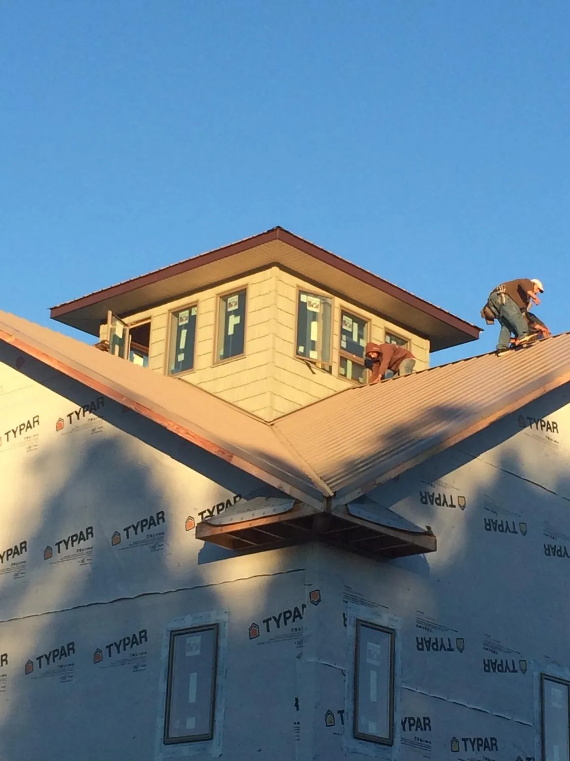 Roofers working around a rooftop cupola on a new metal roof at sunset — Roof Waterproofing in Timberville by Roofing Brothers